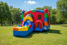 Colorful inflatable bounce house on a grassy field with trees in the background - HullaBalloo Sales