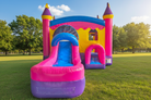 Colorful inflatable bounce house with slide on a grassy field - HullaBalloo Sales